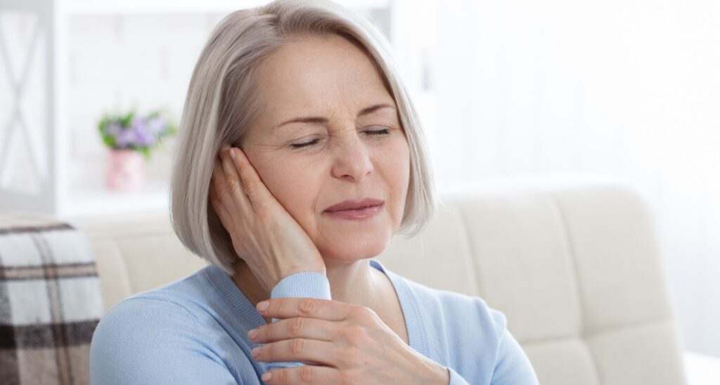 Signora con mano sull'orecchio ed espressione dolorante per il tinnitus